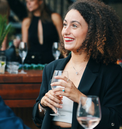 a woman sitting at a table with a glass of wine.